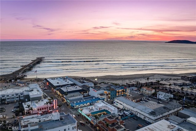 aerial view at dusk with a view of the beach and a water view