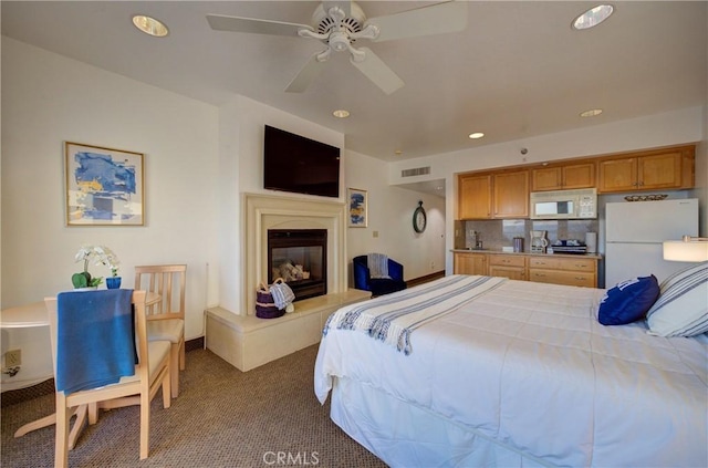 bedroom featuring freestanding refrigerator, dark colored carpet, visible vents, and recessed lighting