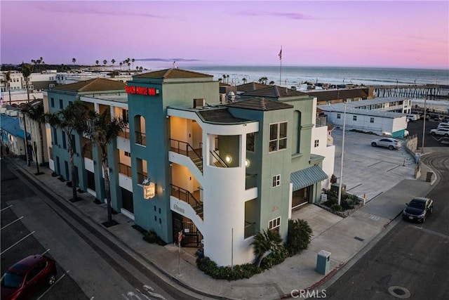 property at dusk with a garage and a water view
