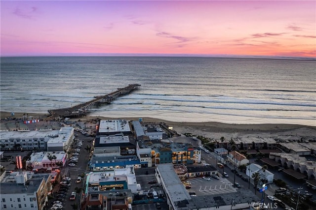 aerial view at dusk with a water view and a view of the beach