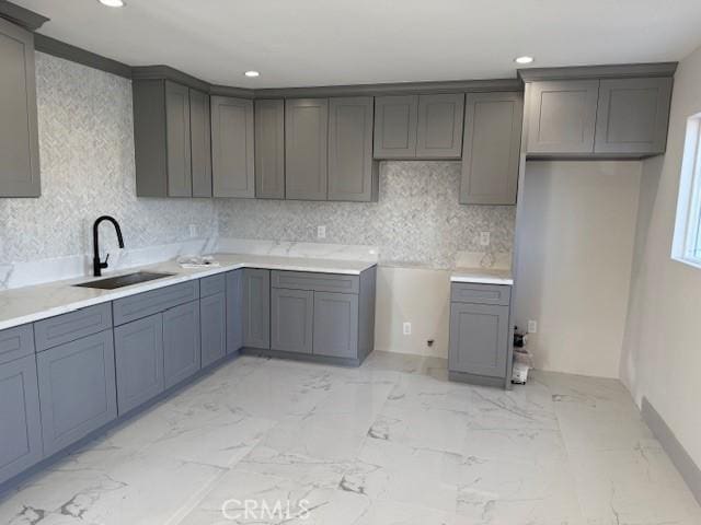 kitchen featuring recessed lighting, marble finish floor, a sink, and decorative backsplash