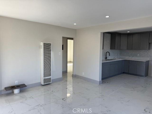 interior space with baseboards, light countertops, a heating unit, marble finish floor, and a sink