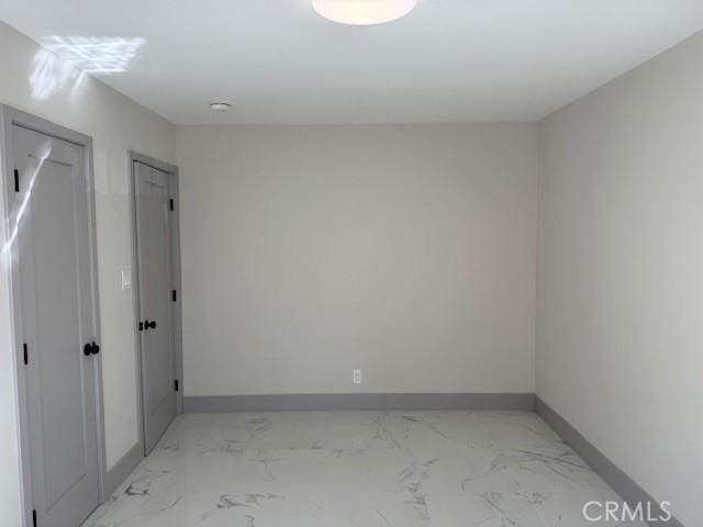 spare room with baseboards and marble finish floor