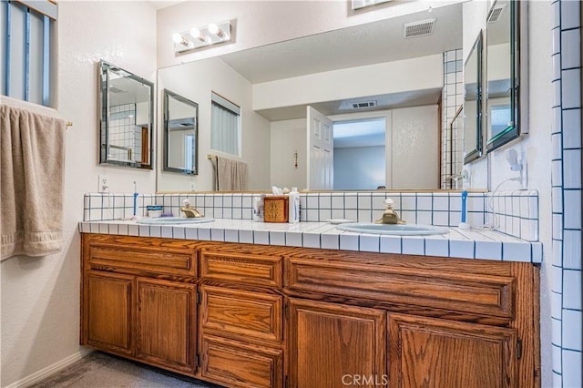 full bathroom with double vanity, a sink, and visible vents
