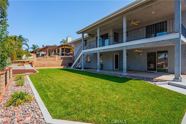 rear view of property with a patio, a balcony, stucco siding, ceiling fan, and a yard
