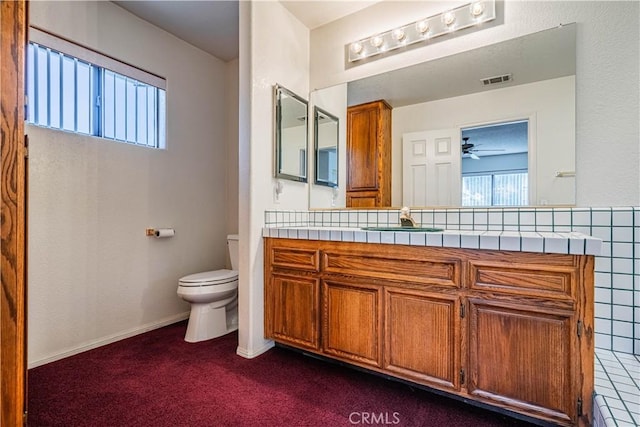 bathroom with toilet, vanity, baseboards, and visible vents