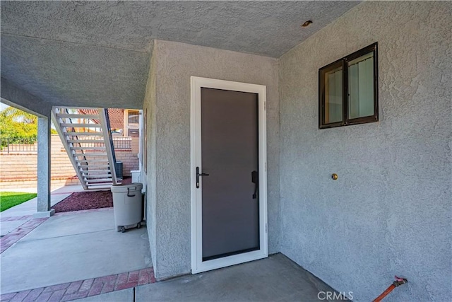 view of exterior entry featuring a patio and stucco siding