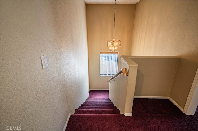 staircase with a textured wall, an inviting chandelier, baseboards, and carpet flooring