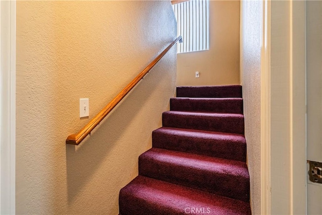 staircase featuring a textured wall