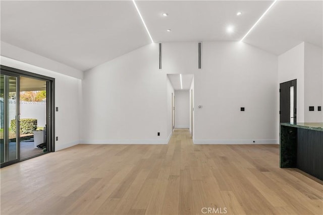 unfurnished living room with light wood finished floors, baseboards, and lofted ceiling