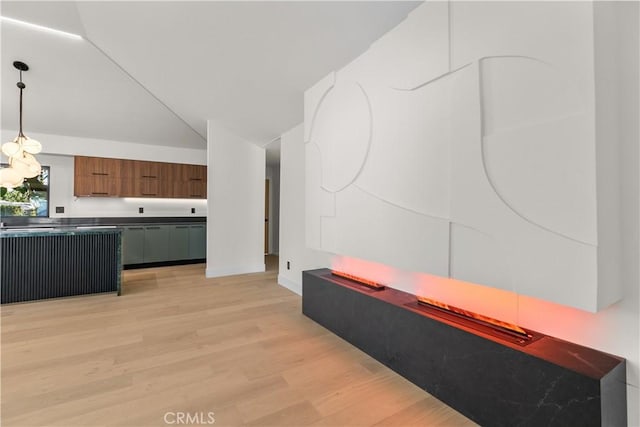 kitchen with decorative light fixtures, modern cabinets, brown cabinetry, light wood finished floors, and vaulted ceiling