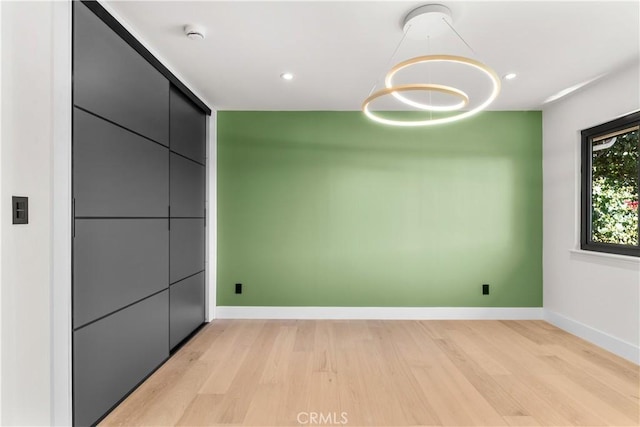 spare room with a chandelier, recessed lighting, light wood-type flooring, and baseboards
