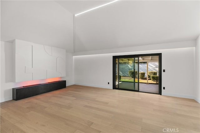 unfurnished room with baseboards, light wood finished floors, and vaulted ceiling