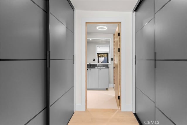 hallway featuring light wood finished floors and a sink