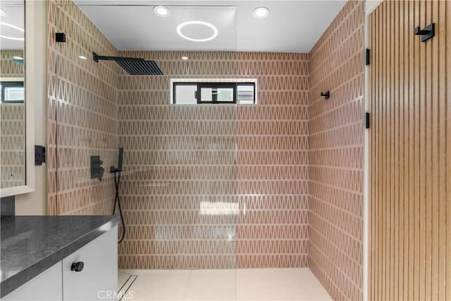bathroom with recessed lighting, tiled shower, vanity, and tile patterned flooring