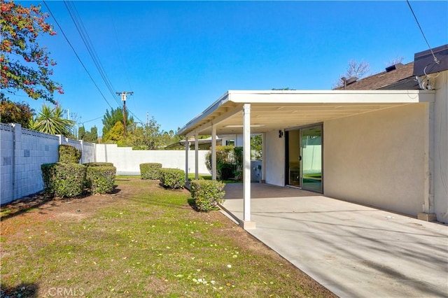 view of yard featuring a carport, fence, and driveway