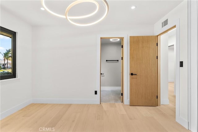 unfurnished bedroom with wood finished floors, a spacious closet, visible vents, and recessed lighting