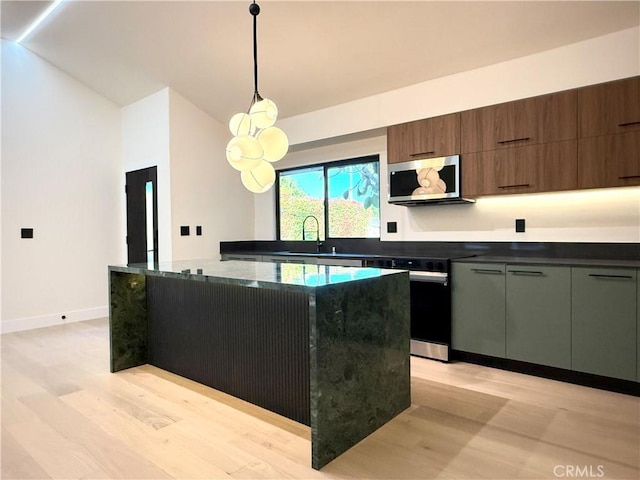 kitchen featuring light wood-style flooring, range with electric cooktop, stainless steel microwave, and a kitchen island