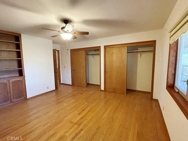 unfurnished bedroom with ceiling fan, two closets, light wood-style floors, and baseboards