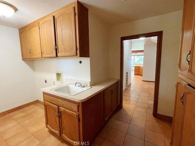 kitchen featuring light countertops, a sink, and baseboards