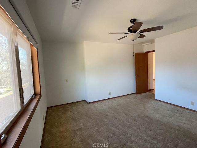 spare room featuring carpet flooring, visible vents, baseboards, and ceiling fan