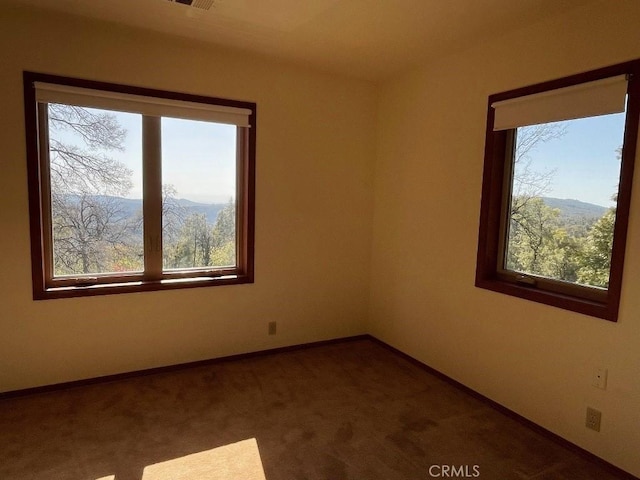 carpeted empty room featuring baseboards, visible vents, and a wealth of natural light
