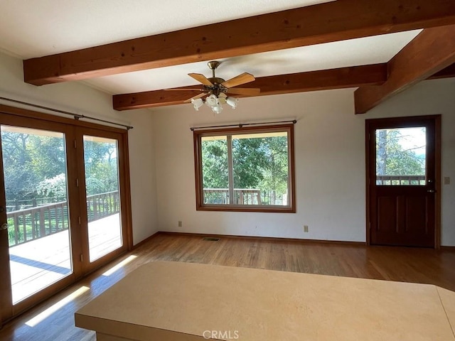 interior space with visible vents, baseboards, light wood-type flooring, and beam ceiling