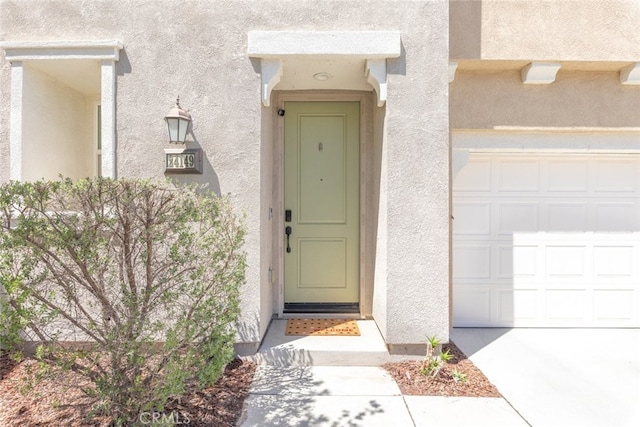 view of exterior entry featuring a garage and stucco siding