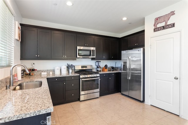 kitchen featuring light stone countertops, recessed lighting, light tile patterned flooring, a sink, and stainless steel appliances