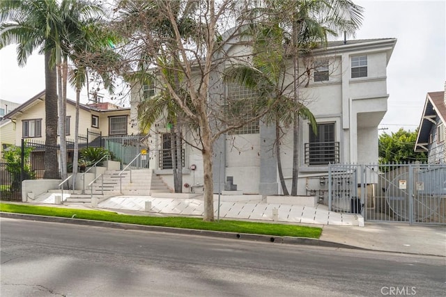 view of front of house with fence, a gate, and stucco siding