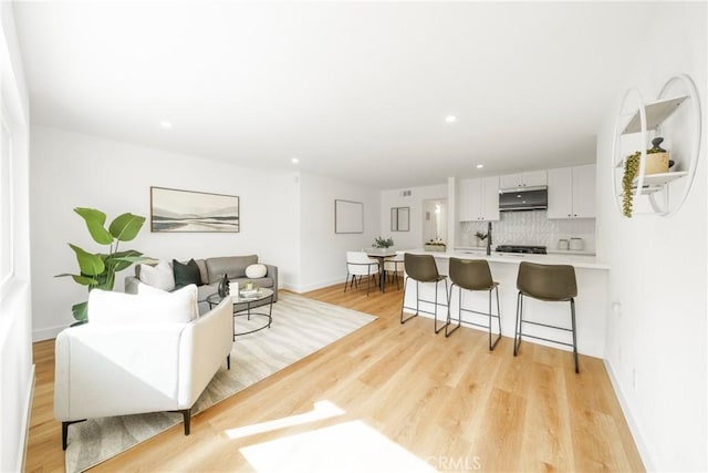 living room featuring light wood finished floors, baseboards, and recessed lighting