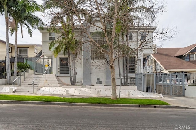 view of front of house featuring fence, stucco siding, and a gate