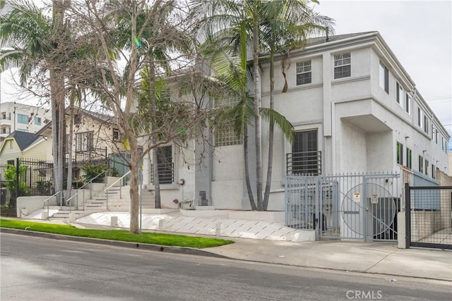 view of front of home featuring stucco siding, fence, and a gate