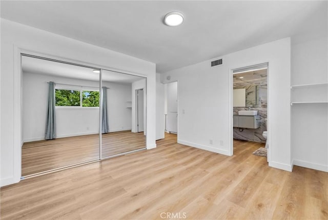 unfurnished bedroom with light wood-type flooring, a closet, baseboards, and visible vents