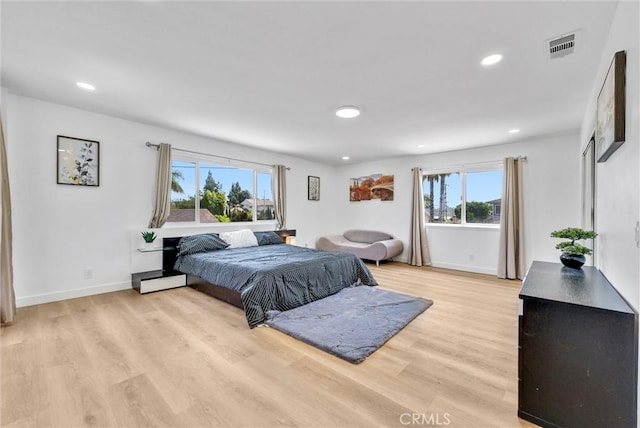 bedroom with recessed lighting, baseboard heating, light wood-style floors, and visible vents