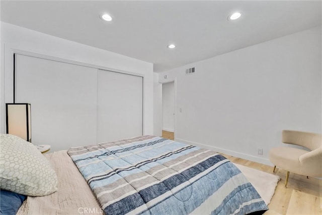 bedroom with a closet, recessed lighting, visible vents, and light wood-type flooring