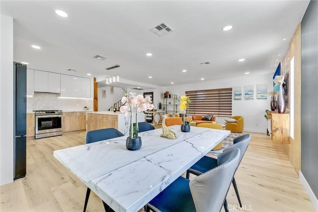 dining area with light wood finished floors, visible vents, and recessed lighting
