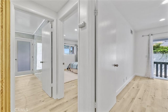 hallway featuring light wood-style flooring, baseboards, visible vents, and recessed lighting