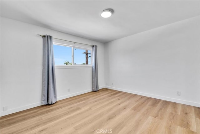 empty room featuring light wood finished floors and baseboards
