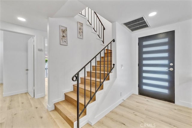 entryway with wood finished floors, visible vents, and stairs