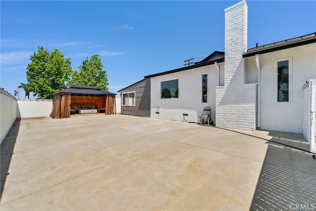 rear view of house featuring a patio area, stucco siding, fence private yard, and a chimney