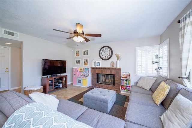 living area with baseboards, a brick fireplace, a ceiling fan, and visible vents
