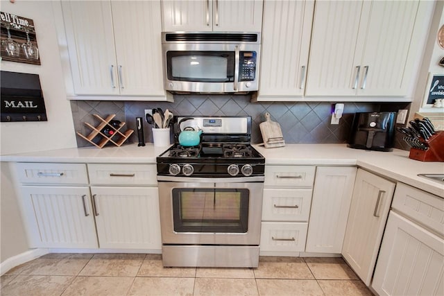 kitchen with light countertops, backsplash, white cabinetry, light tile patterned flooring, and stainless steel appliances