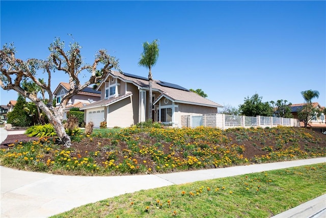 view of side of property featuring an attached garage, stucco siding, fence, and solar panels