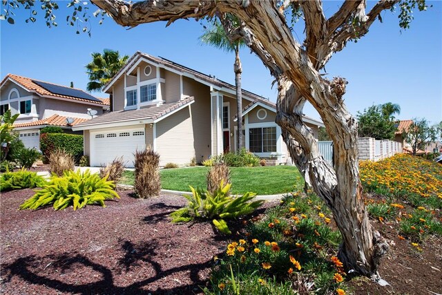 view of front facade with a front yard, fence, and an attached garage