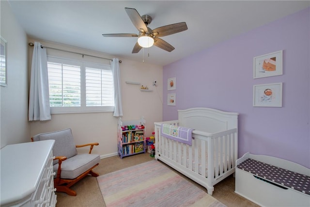 bedroom with a nursery area, carpet floors, baseboards, and a ceiling fan