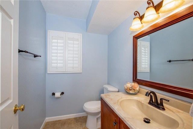 half bathroom featuring toilet, tile patterned floors, vanity, and baseboards
