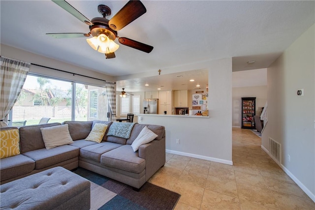 living room with baseboards, a ceiling fan, and visible vents