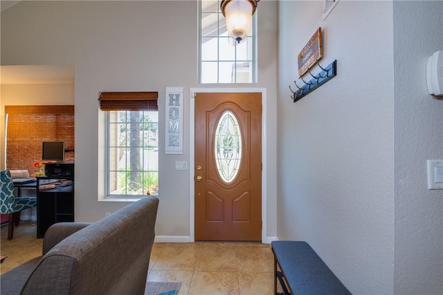 entrance foyer with light tile patterned floors, a high ceiling, and baseboards
