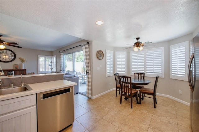 kitchen with a sink, open floor plan, ceiling fan, appliances with stainless steel finishes, and a textured ceiling